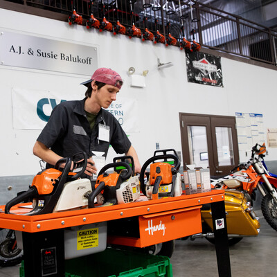 A student performs maintenance on chainsaws.