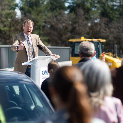 The president of College of Western Idaho speaks to a crowd at an outdoor event.