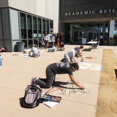 Students draw murals on the sidewalk in front of the CWI Academic building.