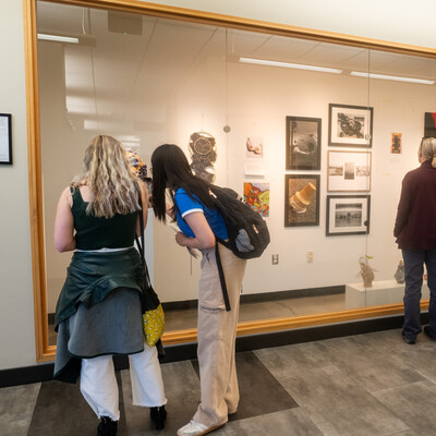 Students and faculty browse artwork displayed on a gallery wall during the CWI 2024 Connections Project.