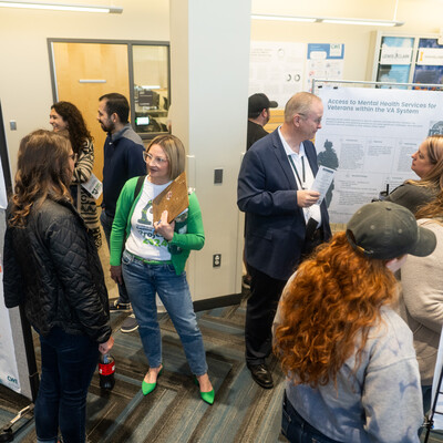 Many students and members of the community stand in front of research posters displayed during the 2024 CWI Connections Project.