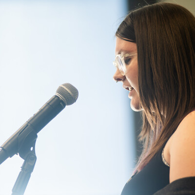 A student reads a short story from a podium during the 2024 Connections Project at CWI.