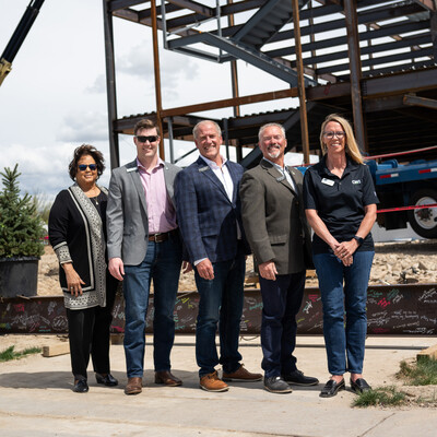 Idaho state legislatures and College of Western Idaho Trustees pose in front of a construction site.