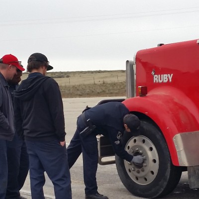 CWI students checking lug bolts on a semi truck bigger shot