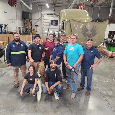 Group of people posing in an automotive space