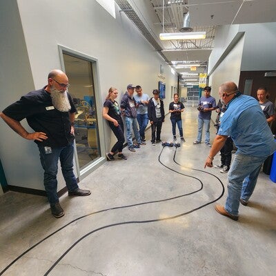 Group of people in a hallway looking at a track on the floor