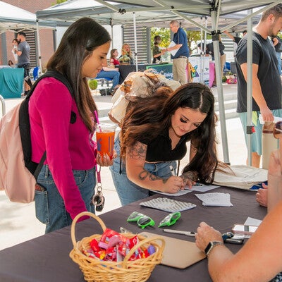 Two students visit booth and sign a paper