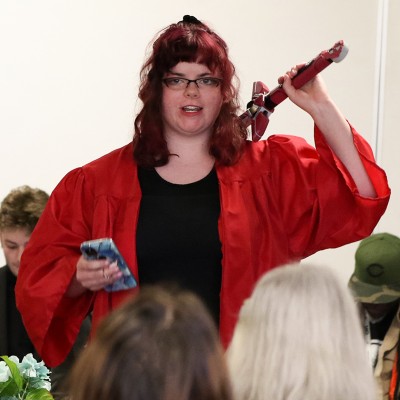 Student performing part of a readers theater in a red robe and holding a sword