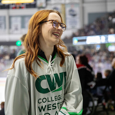 The winner of a scholarship smiles while wearing a CWI hockey jersey during a hockey game.