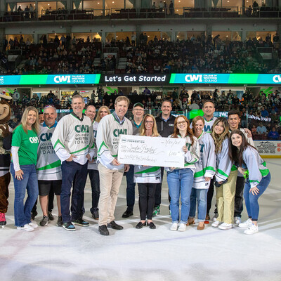 The winner of a $1000 scholarship is awarded a big check on the ice of a hockey rink.