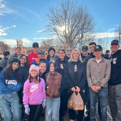 Group of people standing outside in front of tree