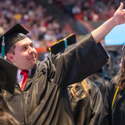Graduate giving a thumbs up to the crowd at commencement