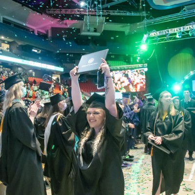 Graduate holding up diploma after commencement