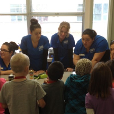 Dental Assisting Program students talking with elementary students.