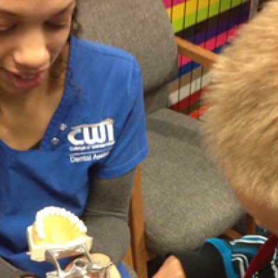 Dental Assisting Program student demonstrating oral health with little boy.