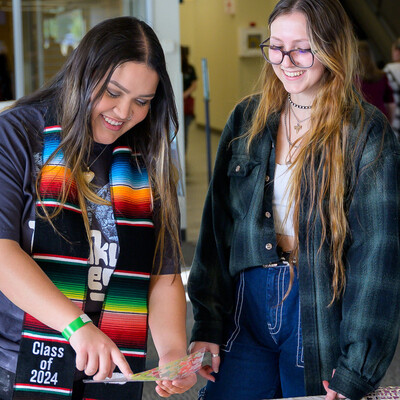 Two students decorate their graduation caps during Grad Fest 2024 at CWI.
