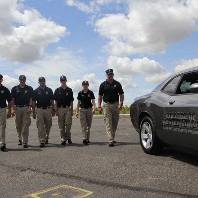 Reid and Law Enforcement students walking on a practice track next to a CWI Law Enforcement vehicle