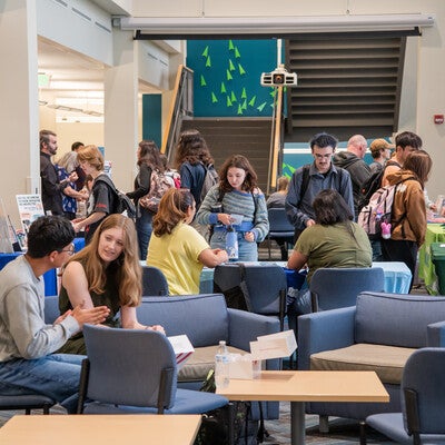 Students chat with staff and clubs around lobby and chairs