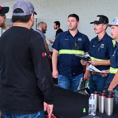 Three students chatting with employers with papers