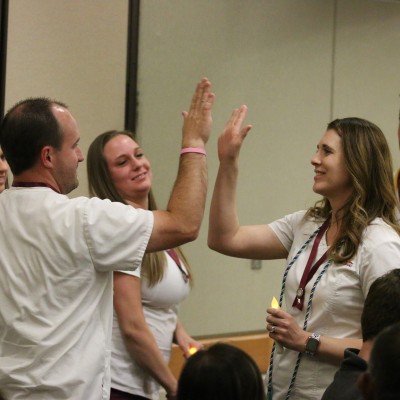 Professional Nursing students high five after pinning ceremony