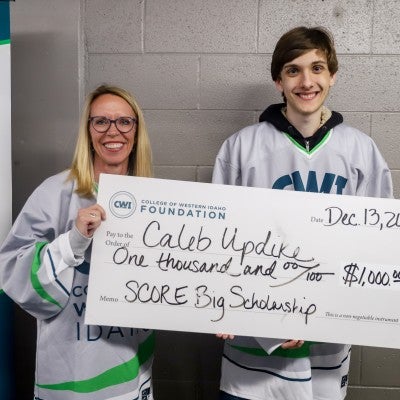 Nicole Bradshaw and Caleb Updike holding up check