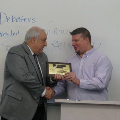 CWI President Bert Glandon (left) presents an award to Speech and Debate Coach Johnny Rowing (right).