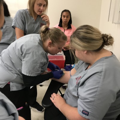 Medical Assistants practicing drawing blood.