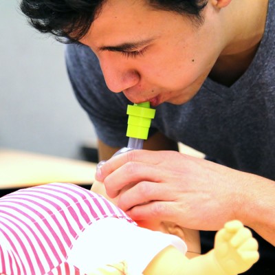 EMS student Daniel Sandoval practices rescue breaths on an infant-sized manikin.