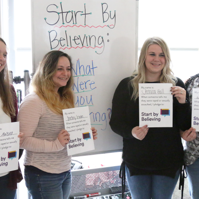 Students holding proclamations signed for Start by Believing Day