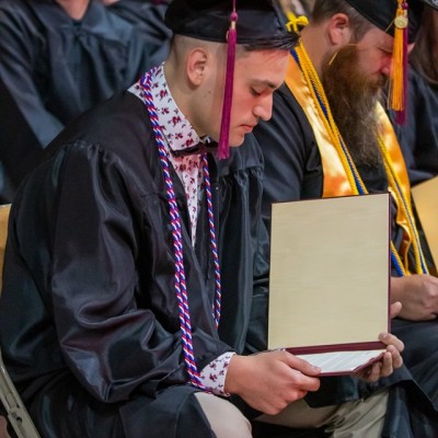 2019 CWI graduate looking at his diploma at Commencement