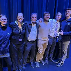 Six students stand in front of a curtain