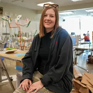 Bronwyn Hitchcock sitting on stool in art classroom