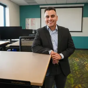 Ismael Garcia stands in front of desk in a classroom
