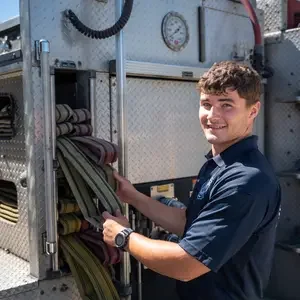 Fire student at a fire truck with a hose