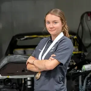 Autumn Harvey wearing her medal in front of a car