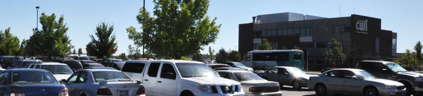 Vehicles in parking lot with CWI building in background.