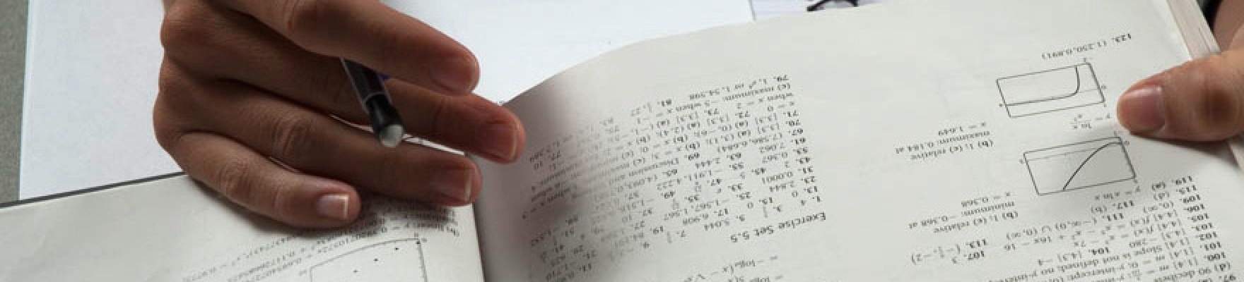 Close up of student's hands holding a math textbook open.