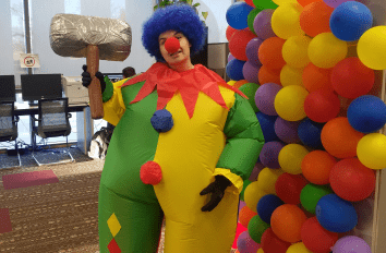Person in blow up Clown outfit with balloons on wall