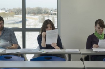 Three Liberal Arts students reading papers.