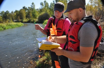Two students in life vest studying a river.