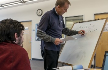 Math tutor helping student by writing on whiteboard
