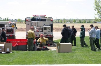 Wildland fire students watching demonstration behind two fire trucks.