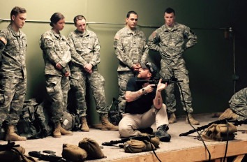 Military science students in uniforms watching a gun demonstration.