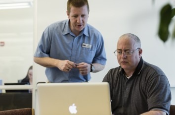 instructor working with student on Apple Macbook