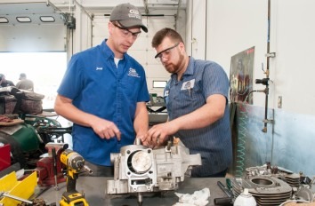 Powersports student and instructor working on a small engine