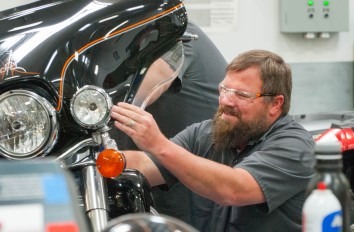 Powersports student working on black Harley Davidson motorcycle