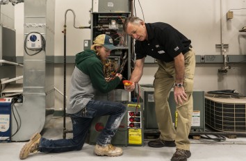 HVAC apprenticeship instructor and student looking at HVAC system.