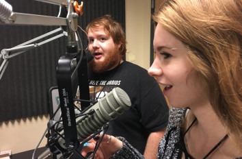 Two media arts students in a recording booth with microphones.