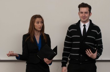 Female student and male student speaking in front of classroom.