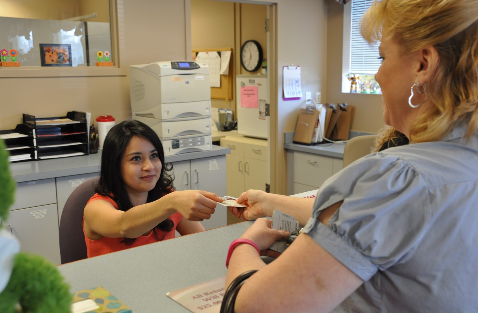 Medical Administrative Assistant handing patient a reminder card
